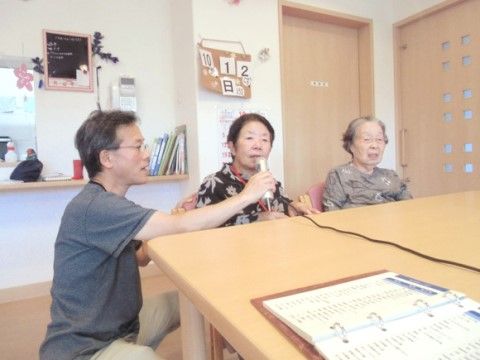 スタッフが持つマイクでカラオケを楽しんでいる入居者様