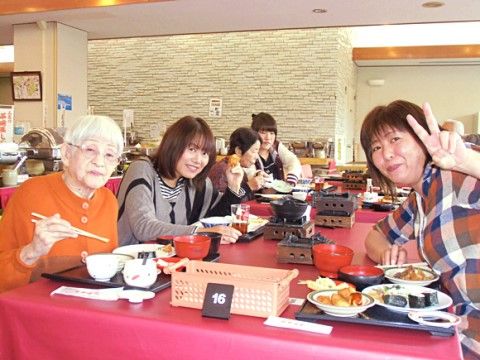 赤いテーブルクロスが敷かれたテーブルに集まって料理を食べている入居者様や関係者