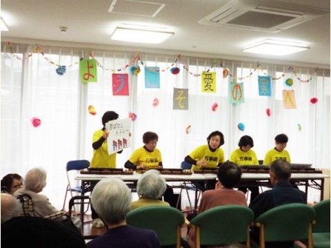 窓際に座っているスタッフたちの話を聞いている入居者様たち