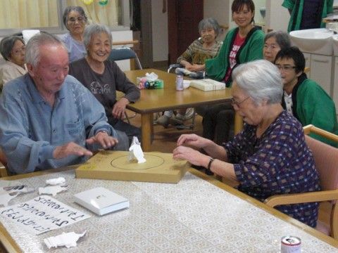 テーブルの上に置かれた紙相撲で楽しんでいる入居者様たち