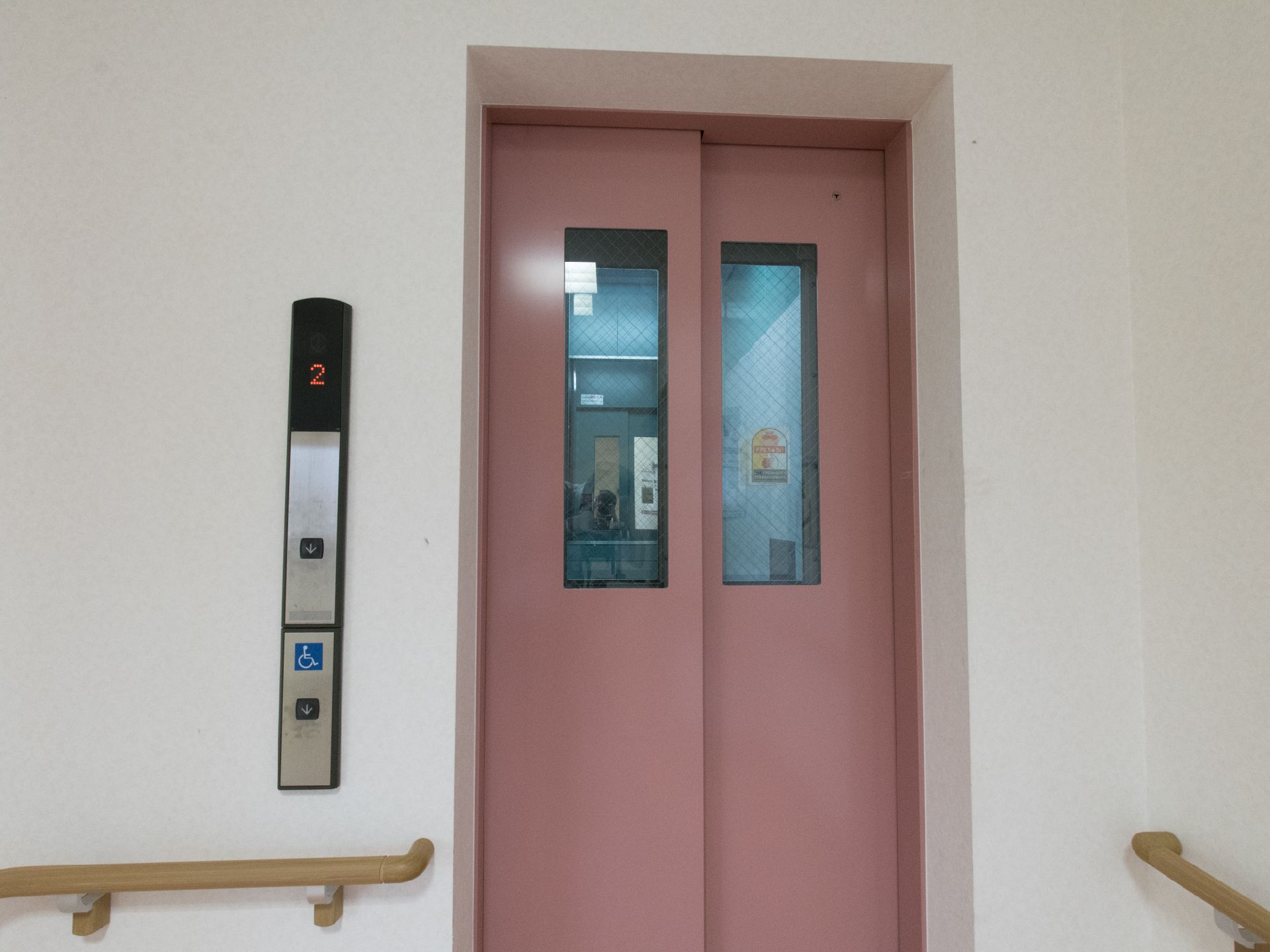 壁全体は白色で茶色の手すりがついている。エレベーターは、ピンクがかっていて、操作ボタンが左手についている。