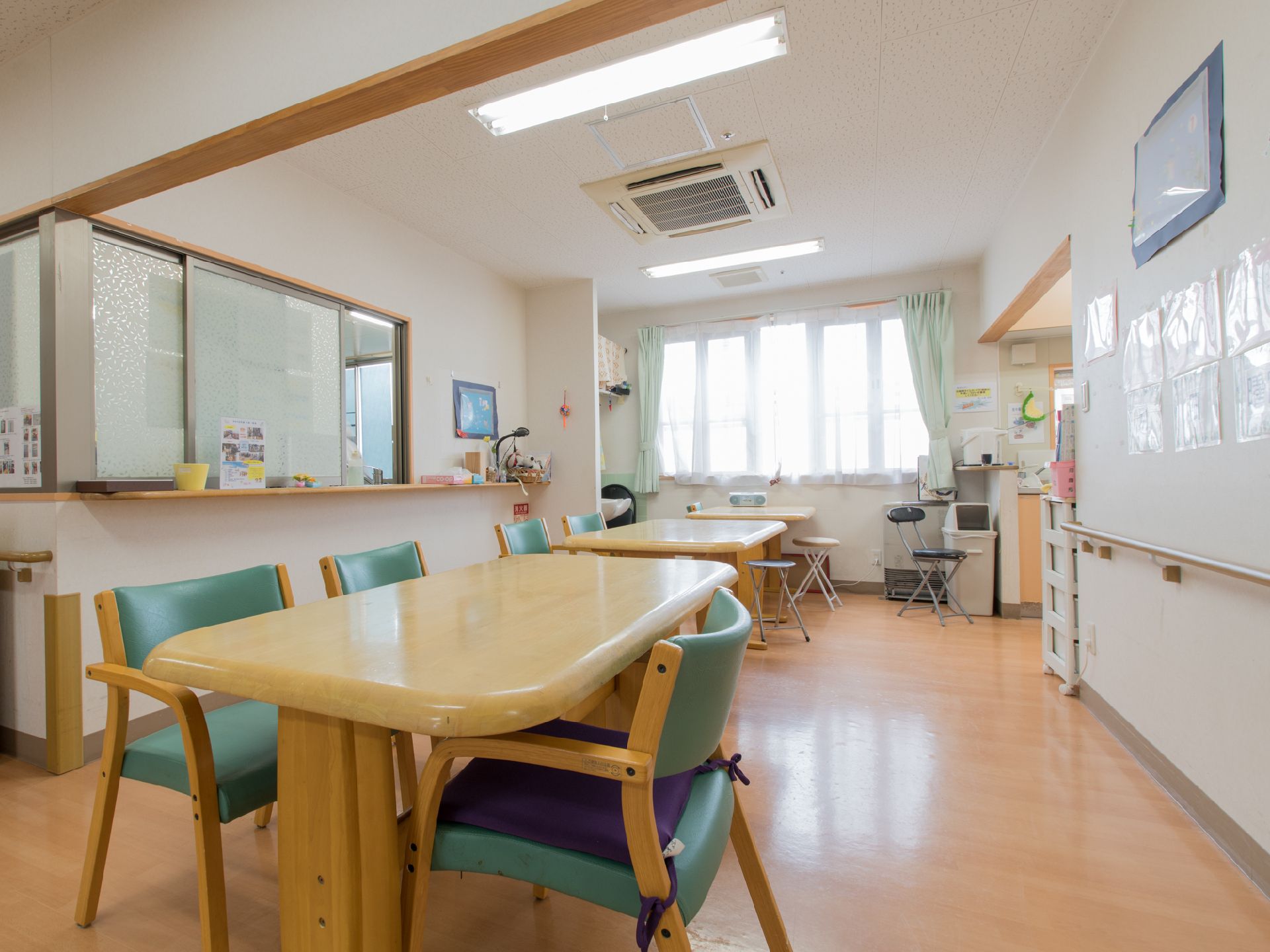 窓からは明るい光が差し込んでおり大きめの木目調のテーブルと椅子が数組置いてある。左側の壁にはガラス戸とカウンターが付いている。