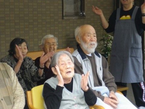 スタッフと一緒に手拍子をしたり笑ったりしている入居者様たち