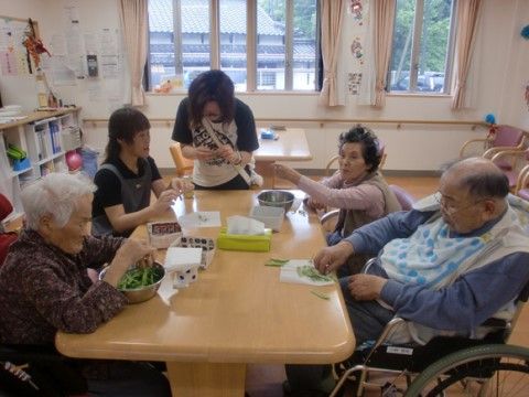 テーブルに集まって、野菜の下処理をしている入居者様たち