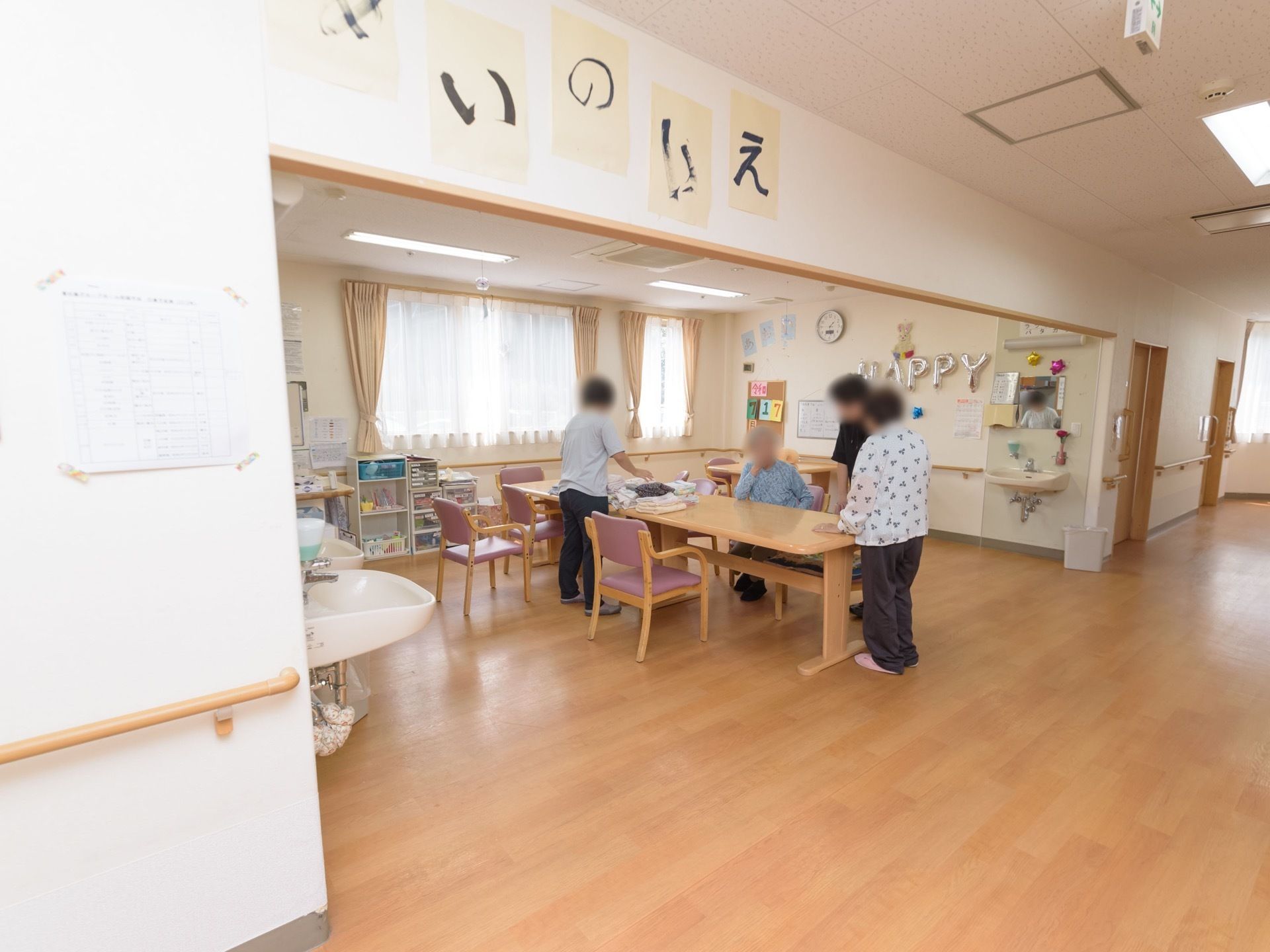 共有スペースにはテーブルと椅子が並べられており、壁には手すりが取り付けられている。洗面スペースもある。