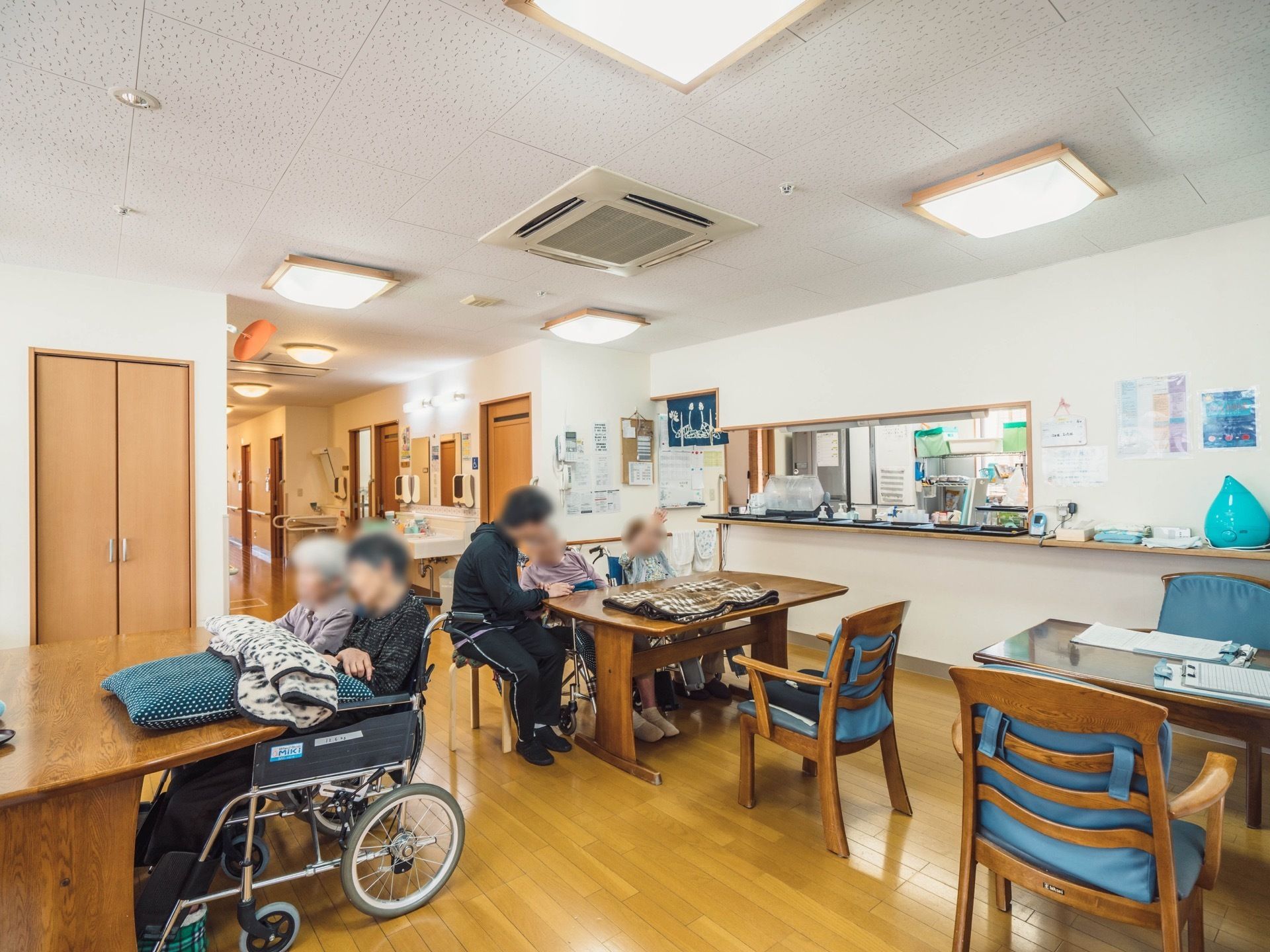 共有スペースでは入居者様がスタッフと会話をしている。車椅子をご利用の方も、ゆったりくつろげる広々とした空間である。