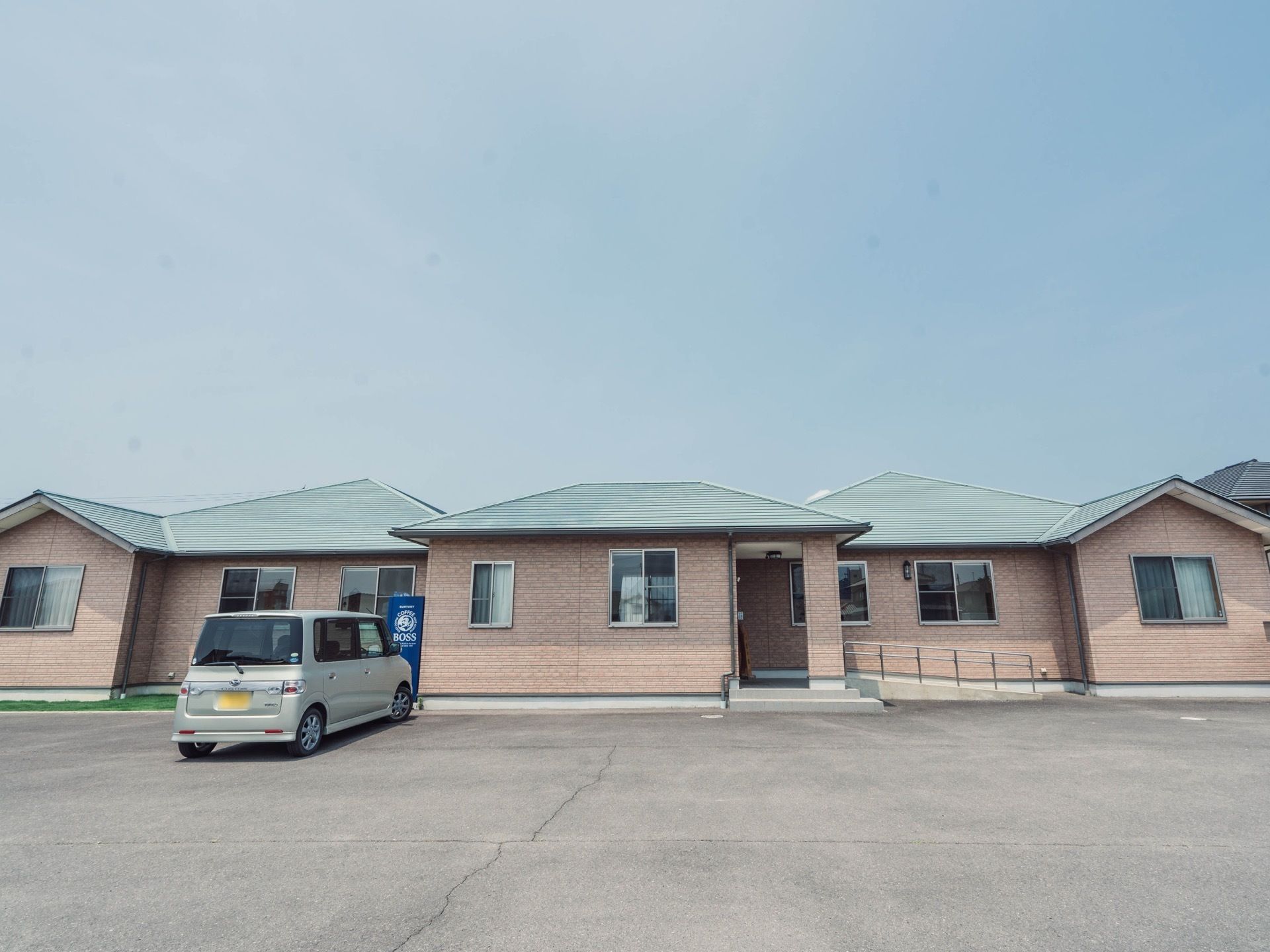 施設の建物は横に長い平屋の１階建てである。グリーンの屋根が特徴的。入口前には広い駐車場が設けられている。