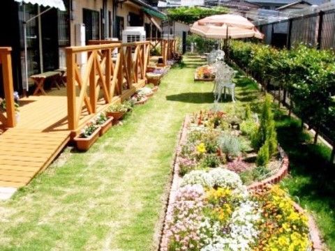 洋風の庭が造られている。ウッドデッキにはベンチがあり、芝生にはパラソル付きのテーブルを設置している。