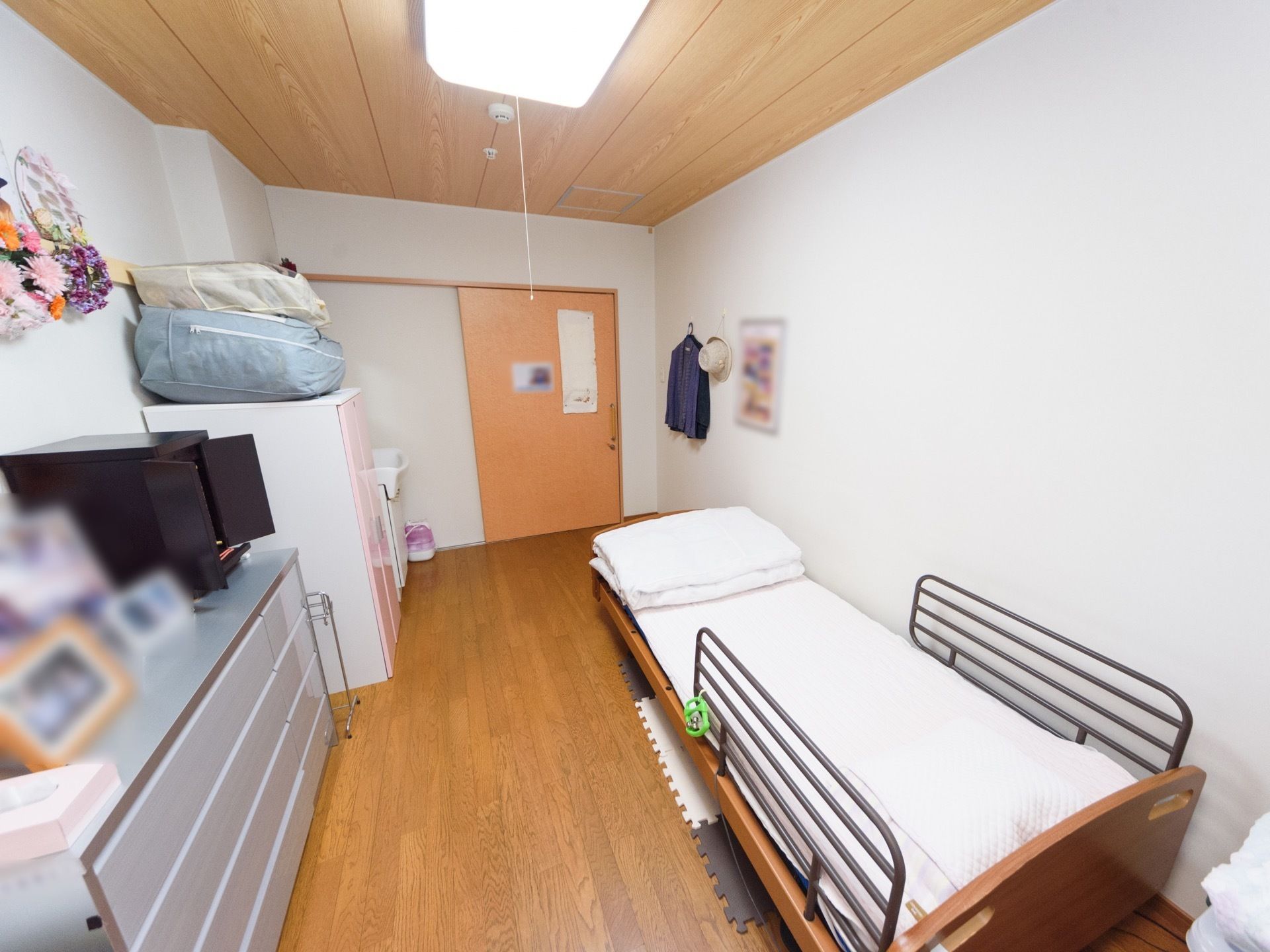 個室の居室である。洗面台が備わっている。介護ベッドや収納家具が置かれている。出入口は、スライドドアになっている。