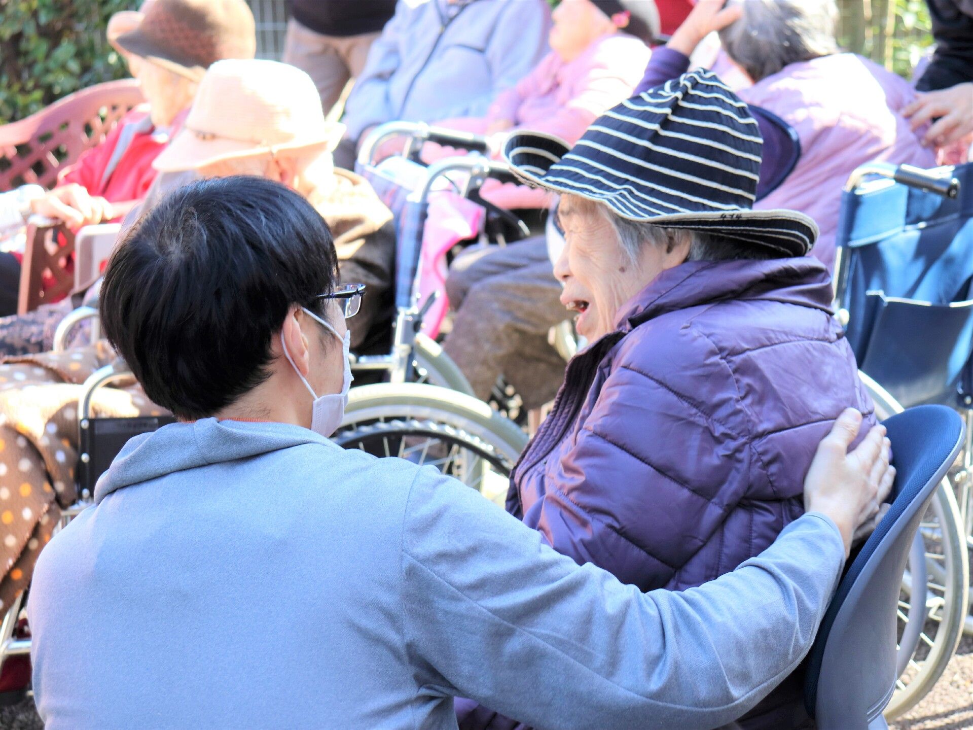 マスクをした男性スタッフが背中に手を当てている女性入居者様