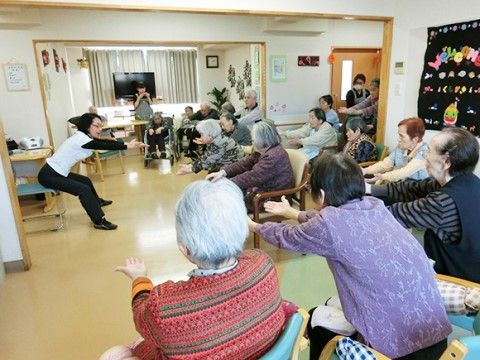 リビングで機能訓練を行う様子。経験豊富なスタッフが、座ったままでできる運動や気軽にできる運動を提案している。