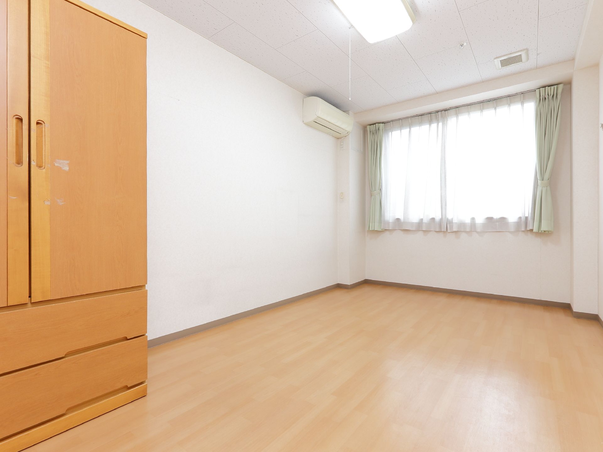 壁は白く、フローリングの床でエアコンが完備してある部屋である。洋式ダンスがある以外、家具らしい家具はない。