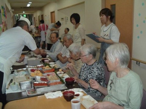お寿司屋さんの訪問を受けて、廊下でお寿司を食べている入居者様たち
