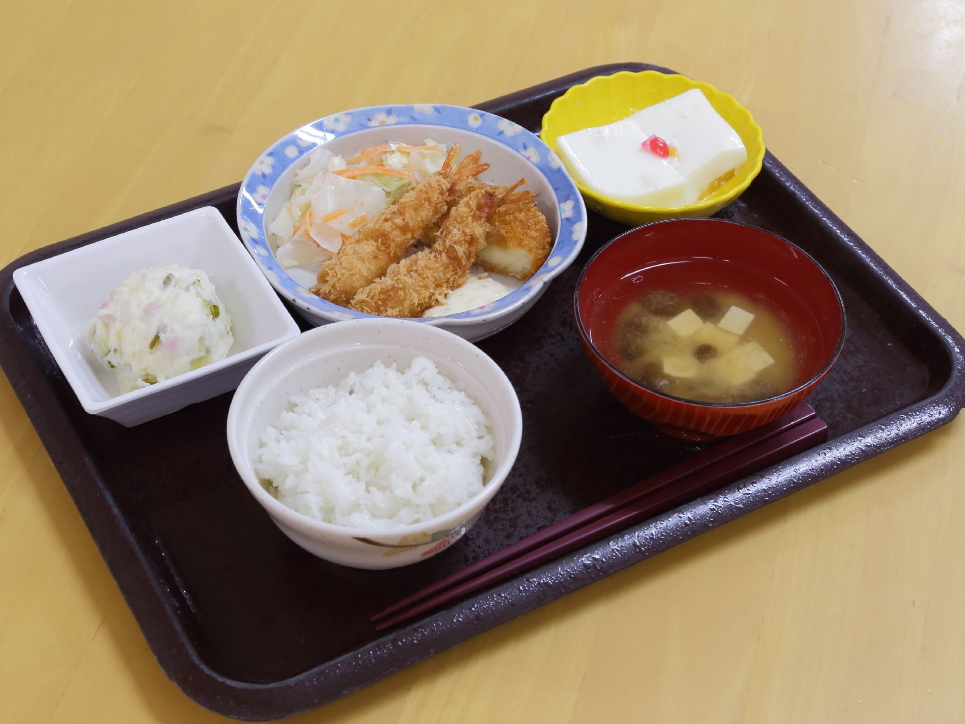 トレーの上にご飯と味噌汁、メインおかずに小鉢が2つセットされた1食の食事である。栄養バランスと品数を考慮された献立である。