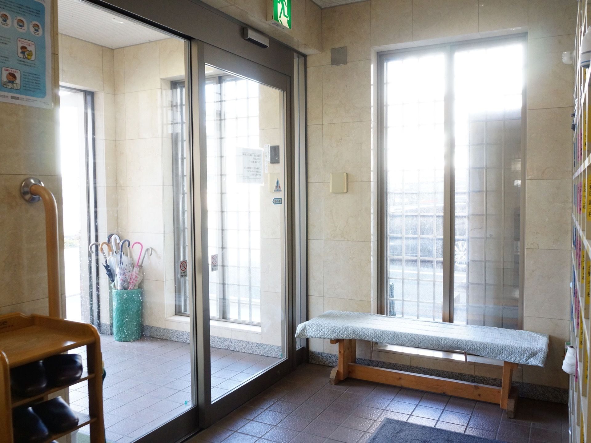 ベンチが置かれている。扉は自動となっている。光が入り、明るい玄関となっている。安全を考え、手すりを設けている。
