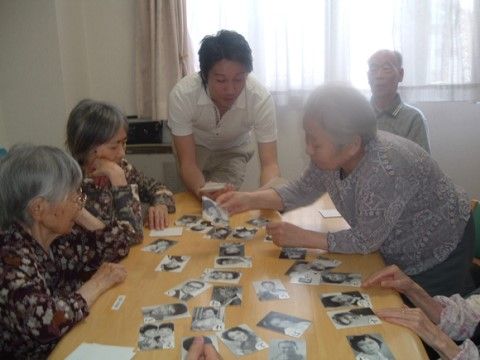 テーブルの上に置かれたたくさんの写真を使った遊びをしている入居者様たち