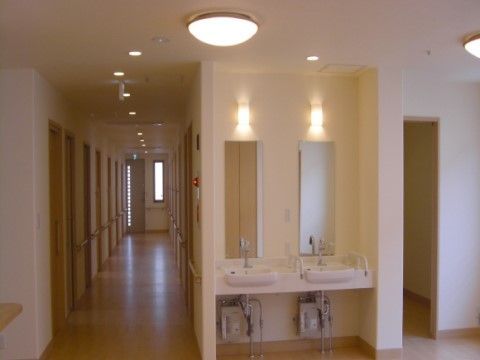 廊下には車椅子でも利用しやすいタイプの洗面台が２基設置されている。大きな鏡も付いているので身だしなみを整えるのに便利である。