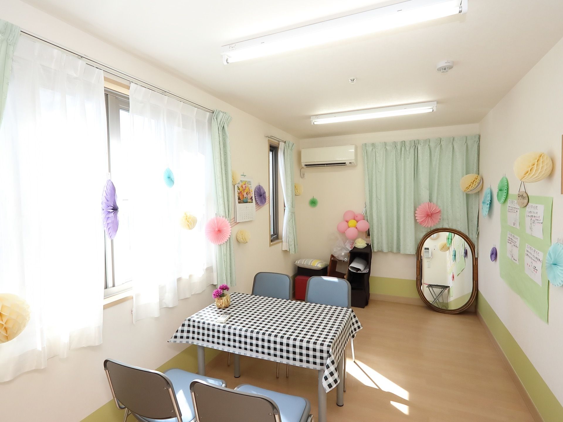 大きな窓がついた、明るい雰囲気の談話室がある。壁やカーテンに、色とりどりの紙で作られたボール状の作品が飾られている。