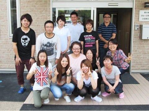 玄関前に集合して、楽しそうに集合写真を撮っている関係者たち