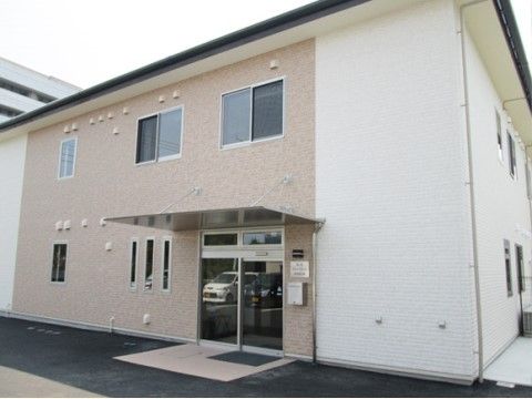 玄関付近の壁面が薄い茶色になっている２階建ての施設外観