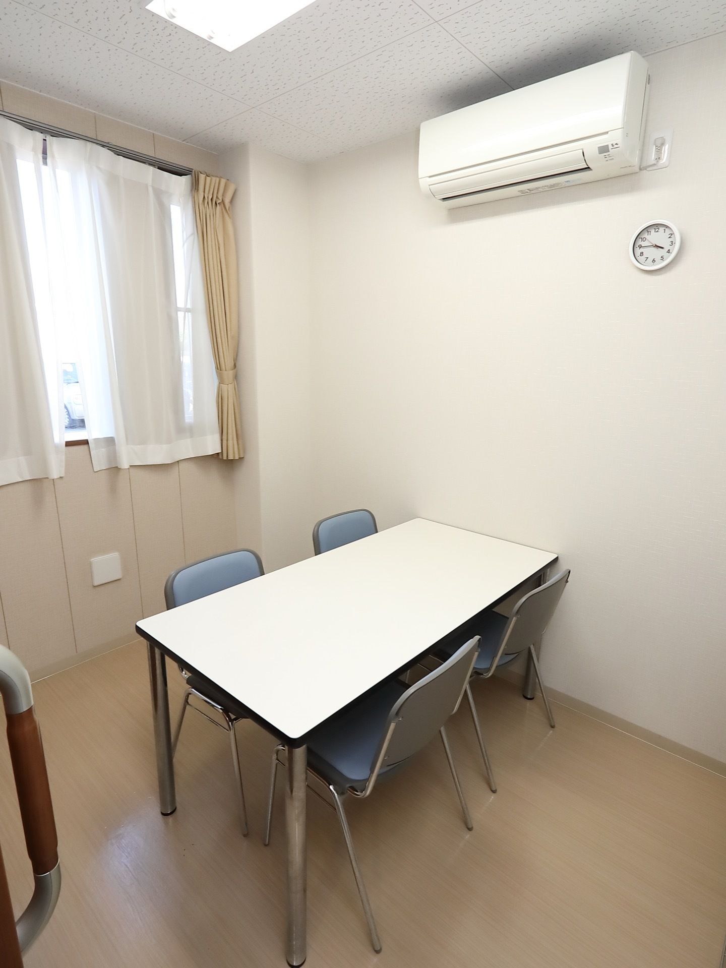 こじんまりとした談話室がある。白色の天板のテーブルと、パイプ椅子が４つ置かれている。エアコンと時計が壁に設置されている。