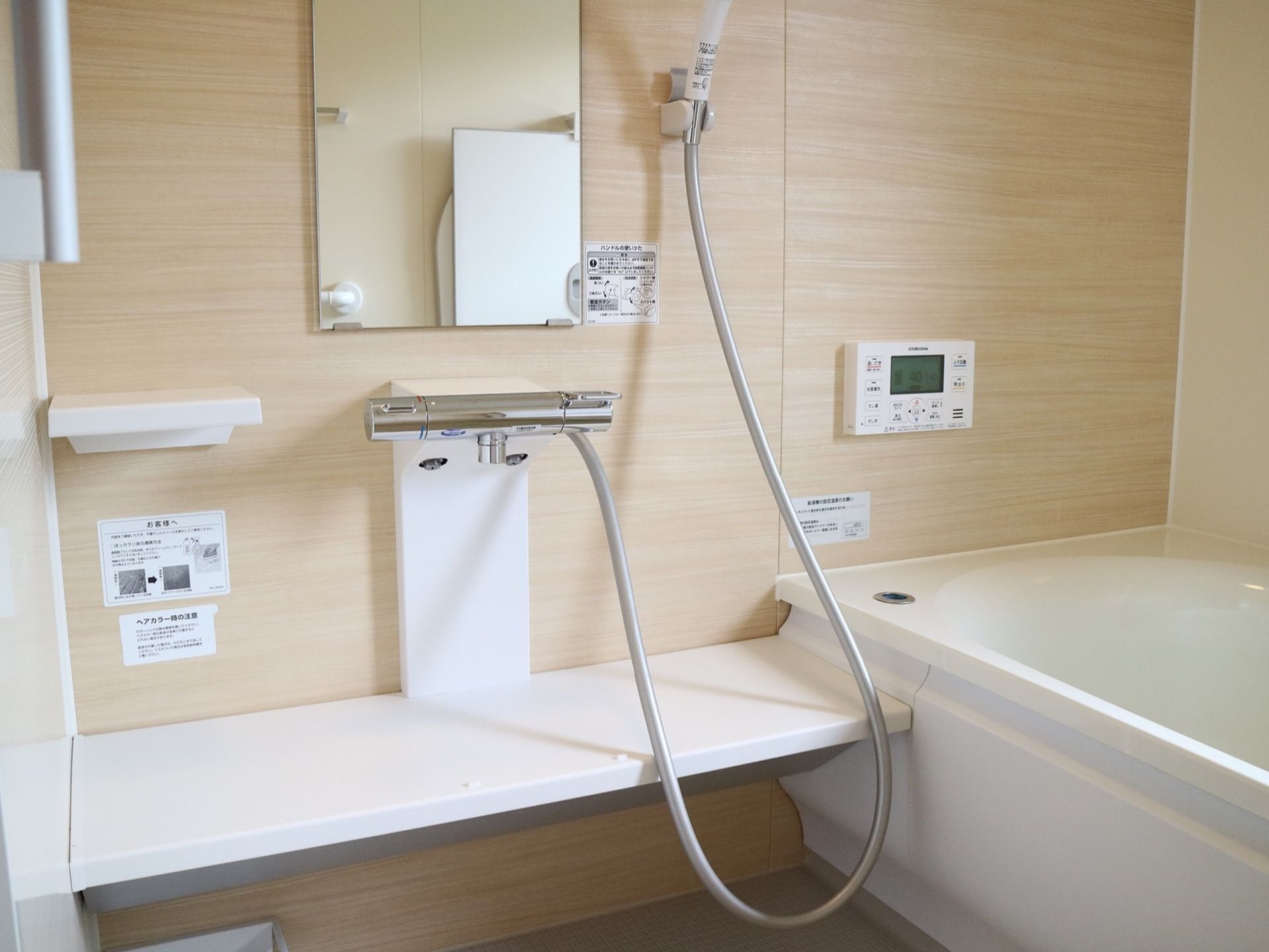 浴室は木目調の壁で癒しを得られるような雰囲気となっている。洗い場にはシャワーや鏡、洗髪用具などが置ける白い台が設置されている。