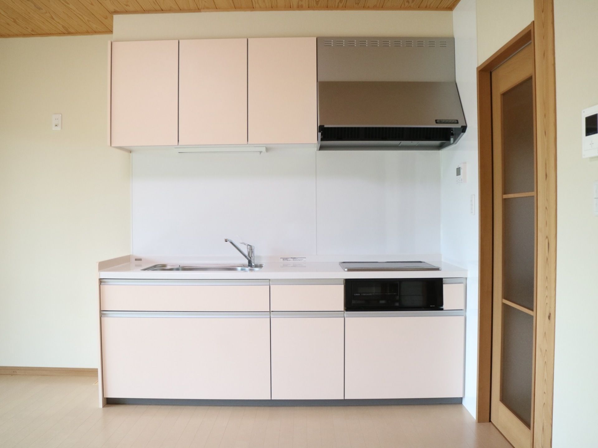 居室のキッチンは、シンクに電磁調理器、魚焼きグリル、大きな換気扇、豊富な収納スペースが完備されている。