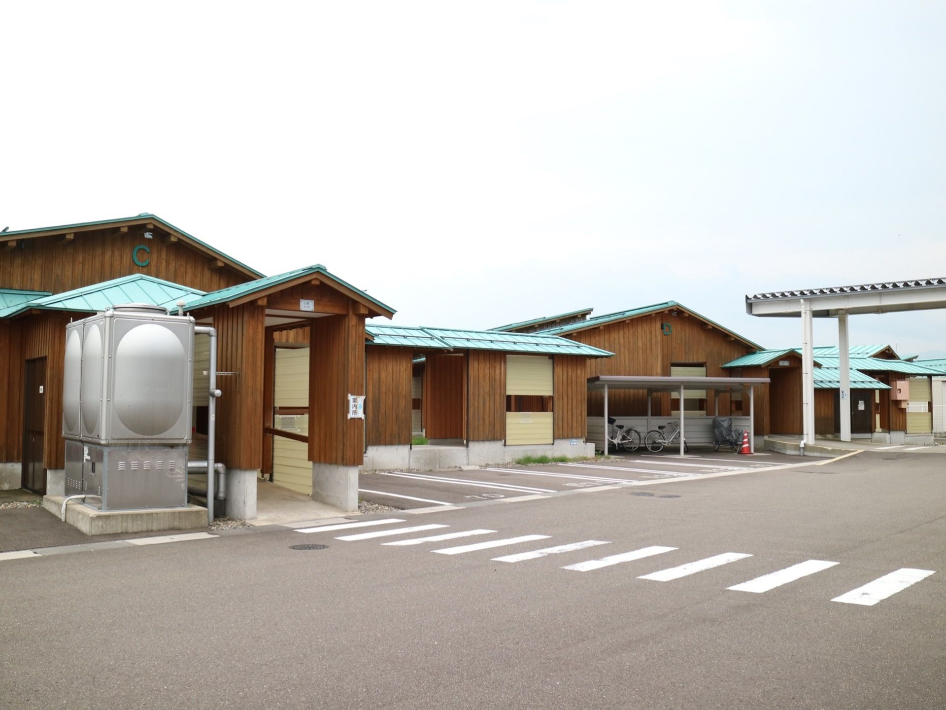 各建物にアルファベットが表示されている。敷地内にはアスファルトで舗装された駐車場や自転車置き場が完備されている。