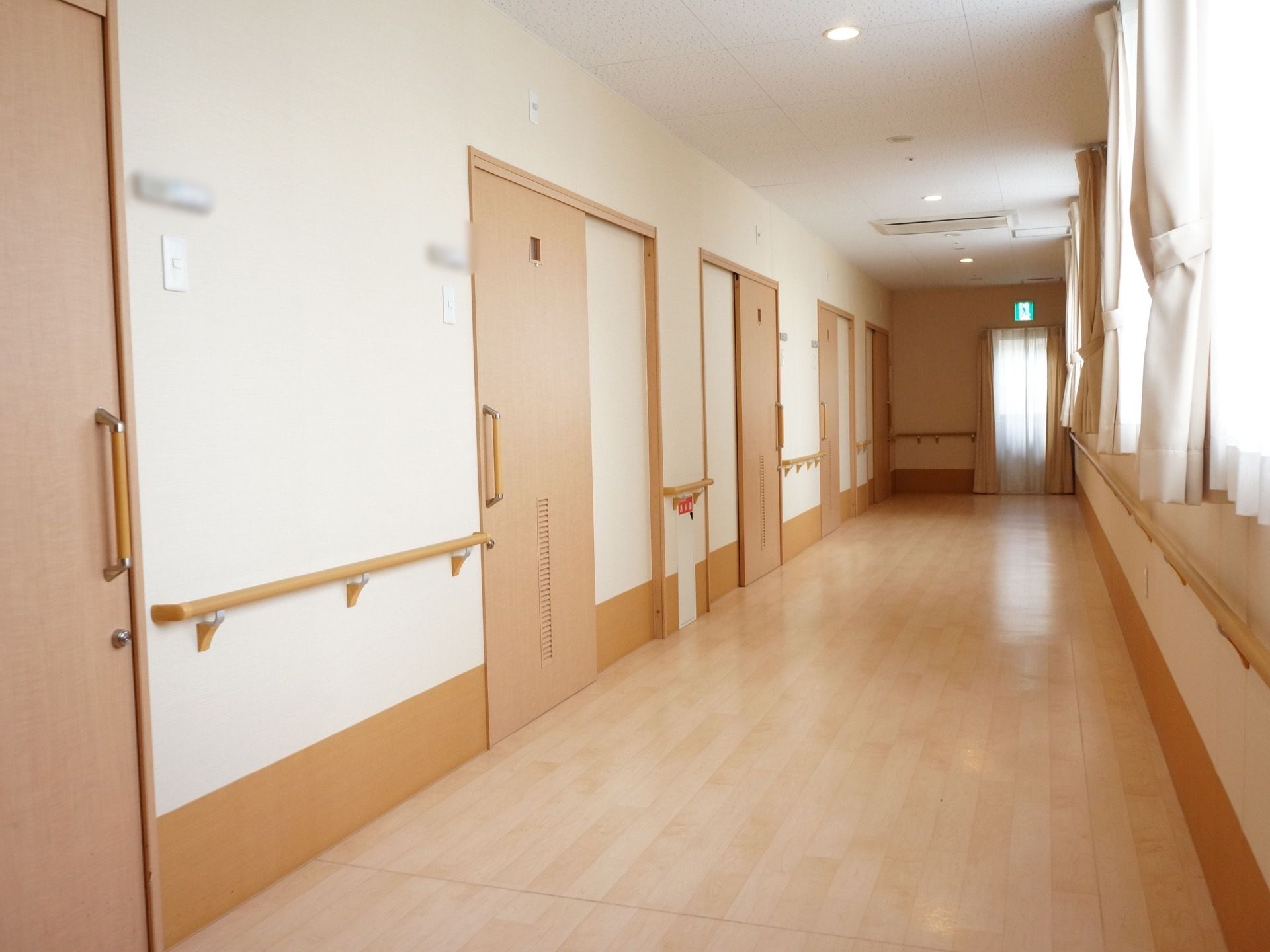 通路の壁は白とベージュのツートンカラーで、居室の扉と床はライトブラウンという、落ち着いた色でまとめられた内装になっている。