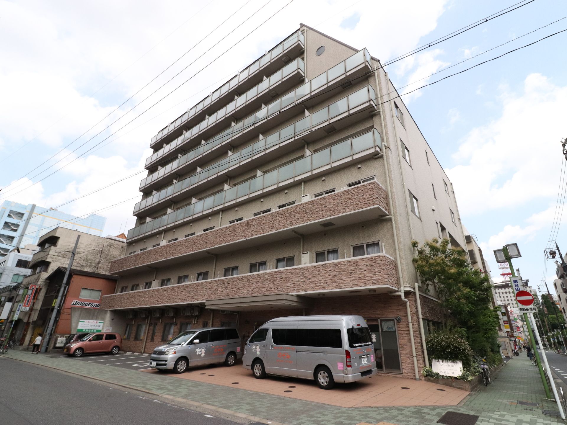 ツートンカラーで8階建ての建物である。施設の前は広い道路になっており、障害物がないので日当たりも良い。