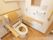 温水洗浄便座付きトイレがあり、木製の背もたれと手すりが設置されている。壁に操作ボタンとナースコールが取り付けられている。