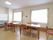 窓が2箇所ある部屋に、揃いのテーブルと椅子が置かれている。壁の一角には、ホワイトボードが設置されている。