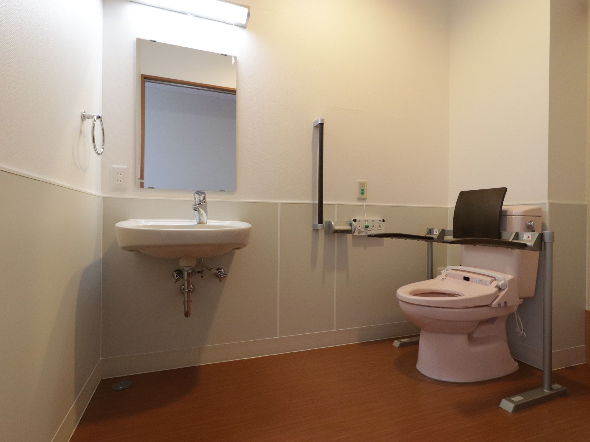 バリアフリーのトイレで、車椅子のまま入居者様が利用することができる。壁に手すりが設置してある。緊急時ブザーがある。