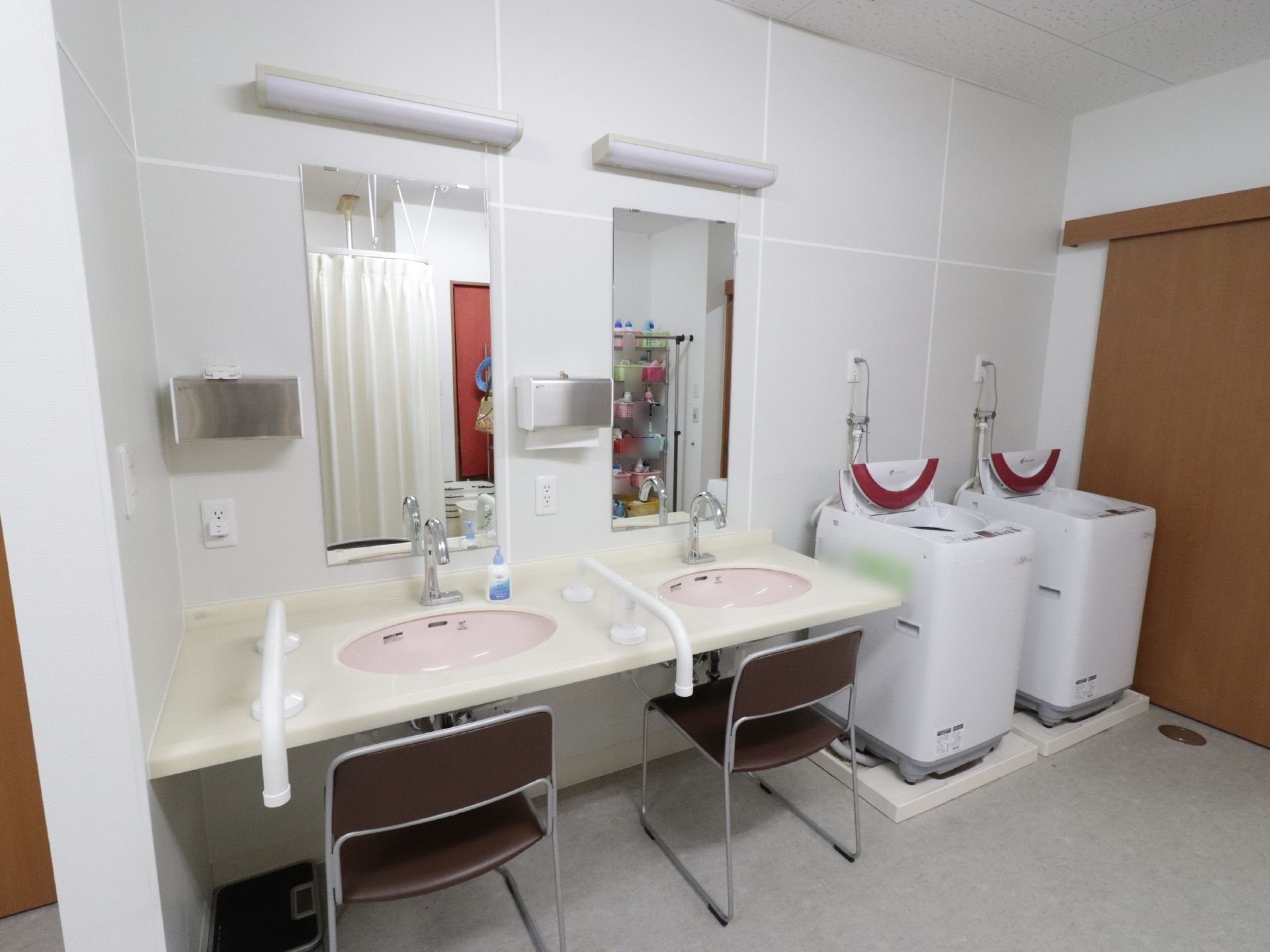 施設にはユーティリティールームがあり、全自動洗濯機が二台置いてある。すぐ横に椅子に腰かけて使うことができる高さの洗面台も完備。