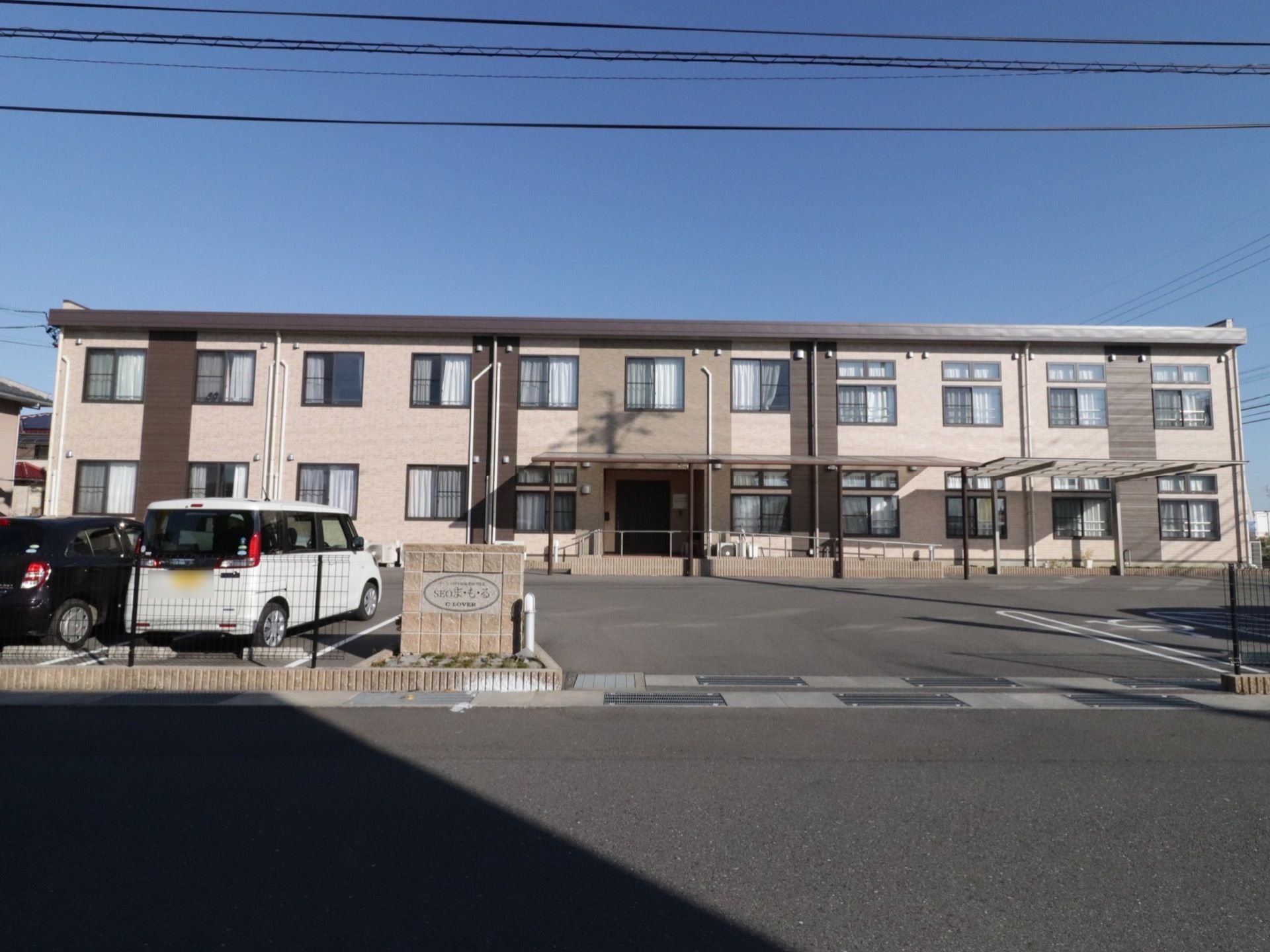 二階建ての施設は、メッシュフェンスで敷地が囲まれている。玄関のそばにはスロープがもうけてあるので、車椅子の入居者様も楽に入退館ができる。