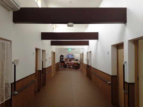 天井の梁が特徴的な廊下は、車椅子同士でも安全にすれ違うことができる幅が確保されている。壁には、手すりが備わっている。