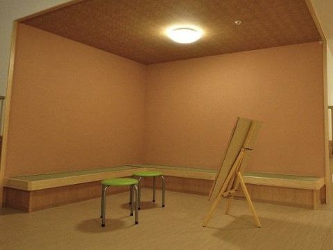 クローバーガーデン富士宮の談話室。壁側に沿ってイスが設置されている。暖色のライトが温かい印象。
