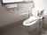 両側に手すりが備えつけられた、洋式のトイレである。広々とした窓を完備。トイレリモコンや壁側に設置されている。