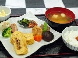 明るい色のお盆に、料理がバランスよく配置されている。本日の料理は和食である。大豆や葉物など、栄養バランスも整っている。
