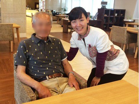 モダンなリビングルームで入居者と笑顔で写真撮影に応じるスタッフ
