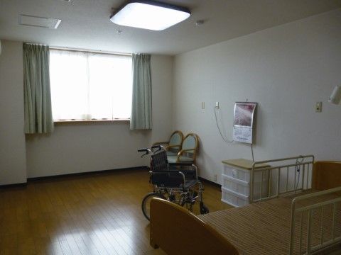 ベッド、車椅子、整理タンス、椅子などが置かれたすっきりとした居室