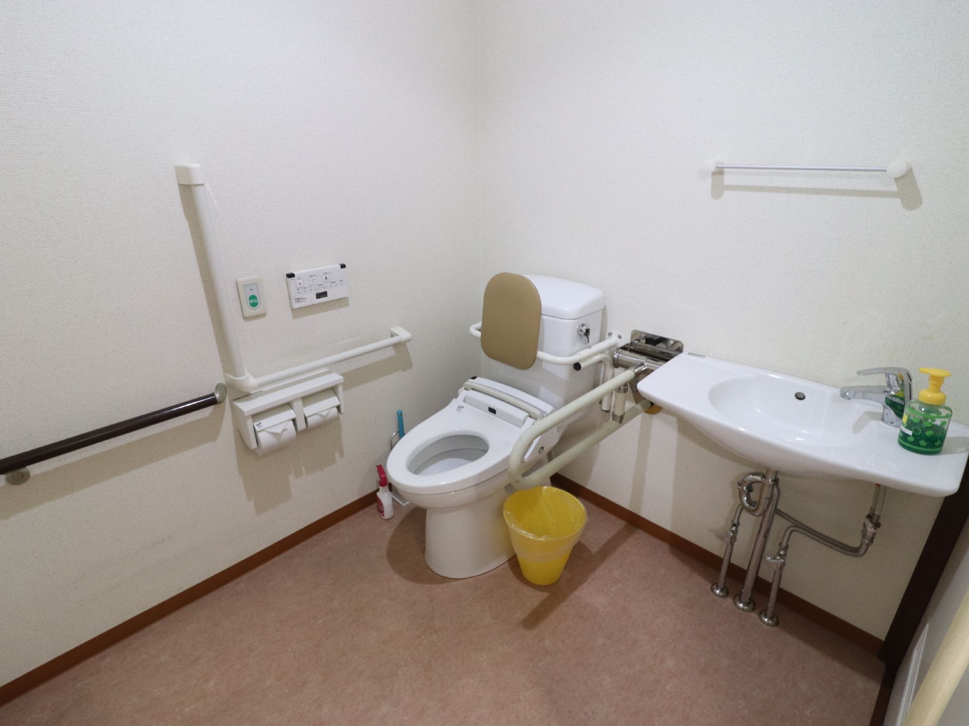 トイレは、フラットな床になっており、広いスペースになっている。手すりが設置され、背もたれも付いている。