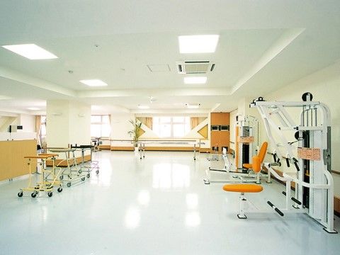 多数の歩行器やトレーニングマシーンがある広くて明るいリハビリ兼トレーニングルーム