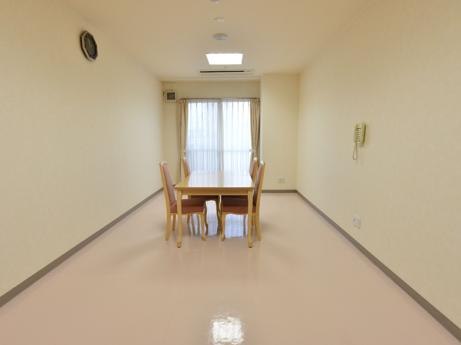 フラットなフロアが広がる一室が談話室となっている。1方向にはカーテンが掛かった掃き出し窓があり、日差しが射し込んでいる。