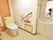 フラットなフロアにトイレと洗面台が設置されている。便座に座って左側の壁には手すりがあり、その下にはナースコールがある。