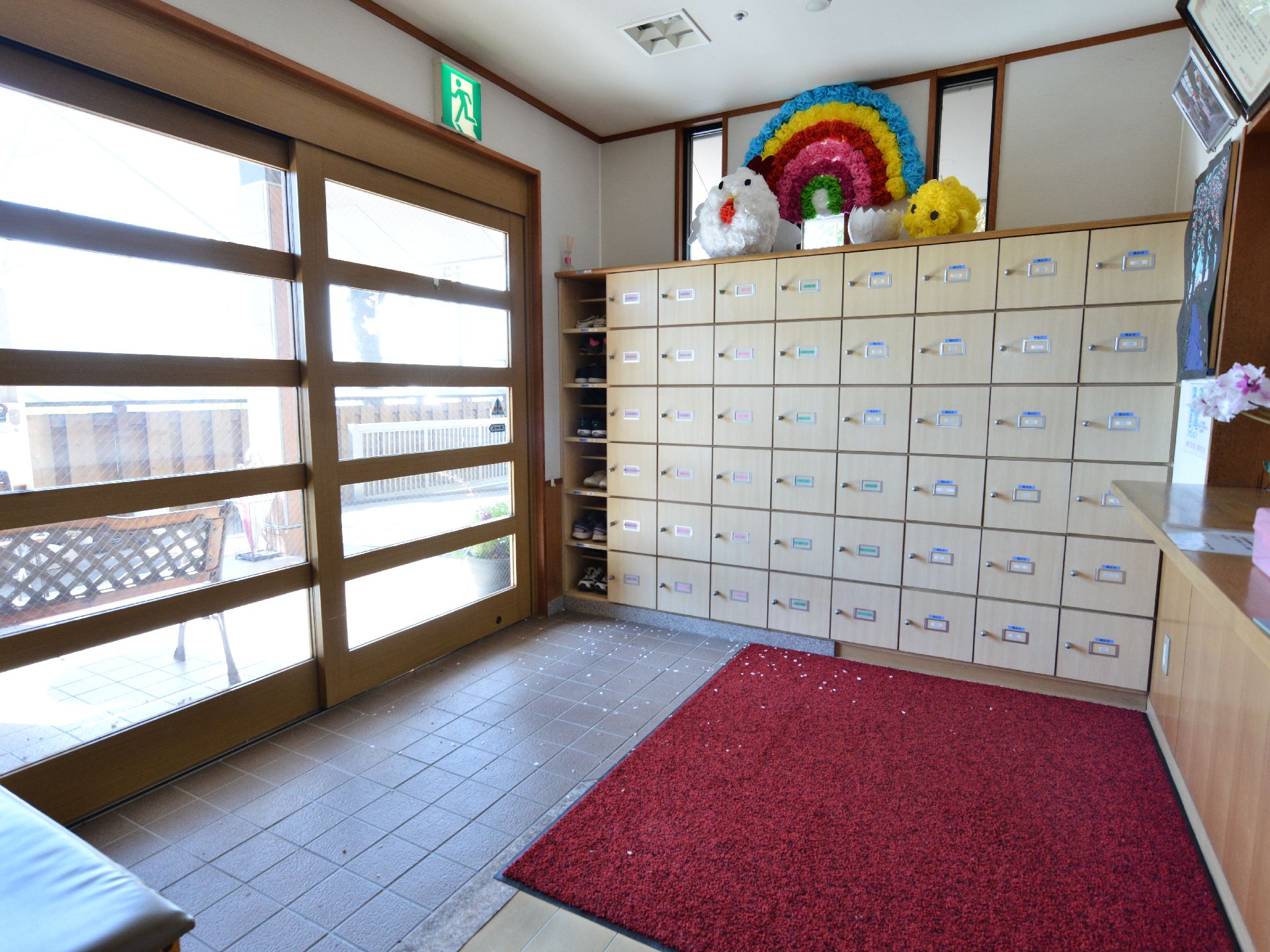 施設の玄関には幅広で大型の自動ドアが設置されている。床は段差は無くバリアフリー構造。靴箱があり赤の絨毯が敷かれている。