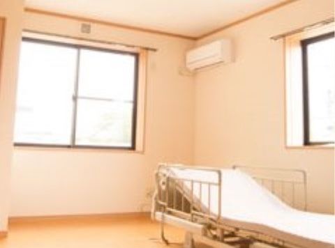 陽当たりの良い、角部屋の居室。壁にはエアコンが取り付けられている。窓際に電動式のベッドが置かれている。