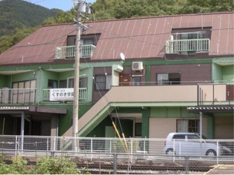 緑豊かな場所に建つグリーンとブラウンカラーの建物
