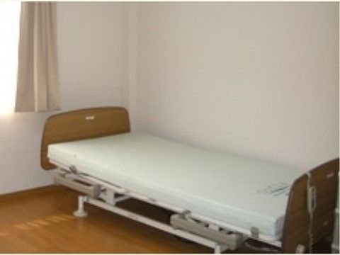 居室の床はフローリングが採用されている。白の壁紙が明るい雰囲気である。介護用ベッドが設置されている。