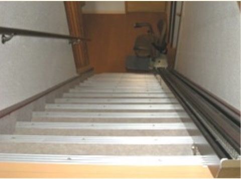 階段に車椅子用リフトが設置されている。反対側の壁には手すりが設けられており、安全性に配慮がなされている。